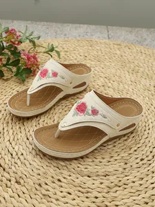 Close-up of stylish women's wedge flip-flops featuring elegant pink floral embroidery