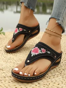 Detailed view of the vibrant floral embroidery on black platform flip-flop sandals.