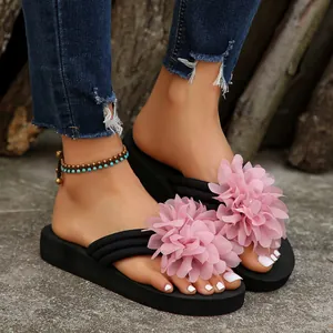 Close-up of stylish women's black platform flip-flops with large pink fabric flowers