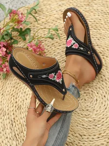 Macro view of black women's platform thong sandals with floral embroidery detail