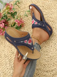 Detailed view of floral embroidery on blue wedge thong sandals for women