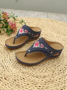 Wedge flip-flop sandals featuring intricate pink rose embroidery on navy straps.