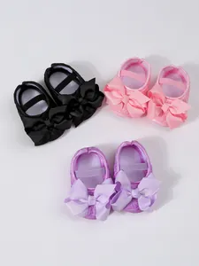 Detailansicht von Baby-Lauflernschuhen in Schwarz, Rosa und Lila mit großen Schleifen.