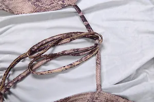 Detailansicht der Neckholder-Gurte mit Schlangenmuster und feinen Nähten an einem Jumpsuit