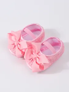 Detailansicht rosa Babyschuhe mit großen Schleifen und weicher Spitzenstruktur für Mädchen.