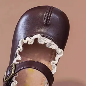 Detailansicht dunkelbrauner Baby Mary Jane Schuhe mit zartem weißen Spitzenbesatz