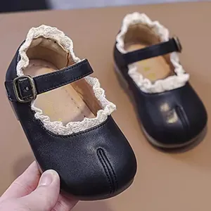 Nahaufnahme schwarzer Baby-Mary Janes mit Spitzenbesatz und Tabi-Design im Detail