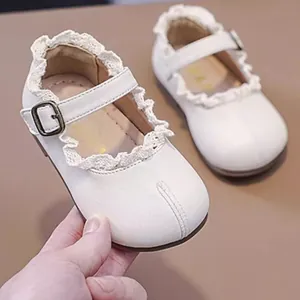 Nahaufnahme weißer Baby-Prinzessinnenschuhe mit Spitzenbesatz und weichem Leder Material