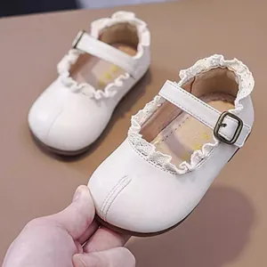 Nahaufnahme weißer Baby-Prinzessinenschuhe mit zarter Spitzenbordüre und weicher Sohle