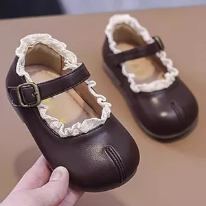 Detailansicht der braunen Baby-Mary-Janes mit zartem Spitzenbesatz und Schnalle