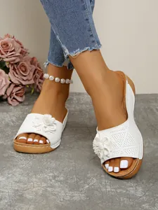 Elegant white wedge sandals with 3D floral decoration being worn on a woman's feet