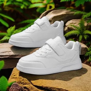 Classic white children's sports sneakers with durable Velcro straps in a natural setting