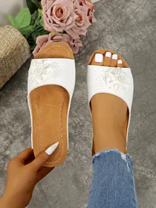 Detail view of white floral wedge slide slippers with perforated upper design