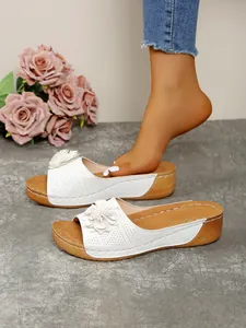 Close-up of white wedge sandals featuring elegant floral decoration and open-toe design
