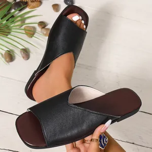 Close-up of black leather V-cut slippers with square toe design on wood floor