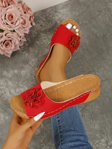 Detailed close-up view of red wedge sandals with leather flower and perforated design