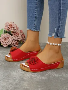 Close-up of red wedge sandals with floral ornament and open toe design for women