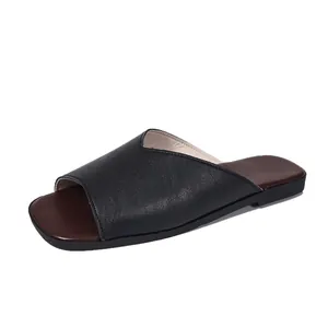 Minimalist black leather V-neck flat slide sandals with square toe and brown footbed.