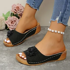 Stylish women's black wedge sandals featuring flower detail and comfortable open toe design