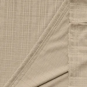 Close-up macro view of beige slub linen-like fabric texture showing detailed seam stitching