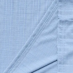 Close-up of light blue breathable faux linen slub fabric with fine grid texture
