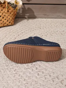 Navy blue closed-toe thick-sole mules with brown textured rubber outsole for grip