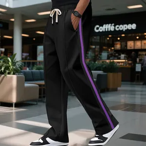 Detail view of men's black high-street sweatpants with purple side stripes and flared leg