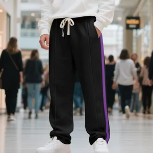 Close-up of men's black flared sweatpants with purple side stripes in a mall scene.