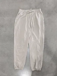 Detail view of men's lightweight linen jogger pants in beige with drawstring waist.