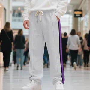 Detail view of grey high-street hip-hop sweatpants with purple side stripes on model