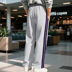 Detail view of men's grey flare sweatpants with purple side stripes in a lifestyle setting
