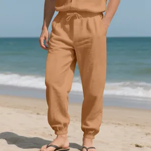 Men's casual loose linen jogger pants in tan color styled for a summer beach look.