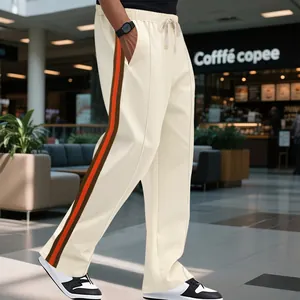 Close-up of men's off-white flared sweatpants with orange and brown side stripes.