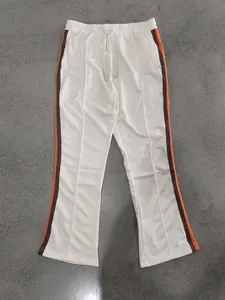 Detailed overview of off-white flared sweatpants featuring orange and brown side stripes.