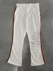 Detailed view of off-white flared sweatpants with orange and brown side stripes for men