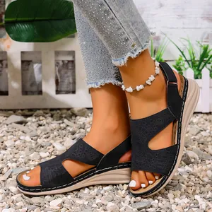 Detail van zwarte retro zomer sandalen met uitgesneden patronen en sleehakken aan de voeten