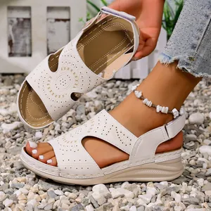 Detailopname beige zomersandalen met ingewikkelde lasergesneden patronen.