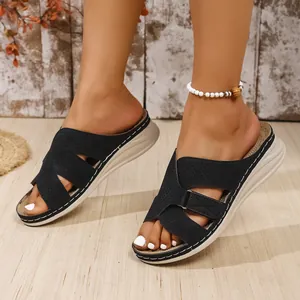 Close-up of black perforated wedge sandals featuring a stylish cross-strap design