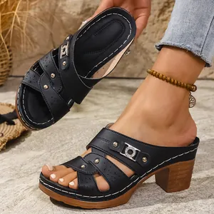 Detailed view of black chunky-heeled sandals with cut-out patterns and metallic accents