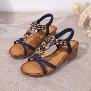 Close-up of bohemian wedge sandals featuring navy straps and intricate beaded details.