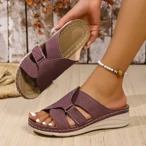 Close-up of purple wedge sandals with perforated cross straps and a thick beige sole.