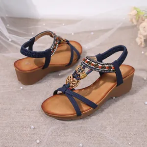 Detailed view of navy Bohemian wedge sandals with intricate embroidery and charms.