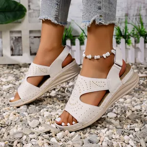 Detailopname van witte zomerse sandalen met open teen en een retro opengewerkt patroon.