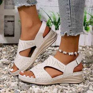 Gedetailleerd overzicht van witte zomerse sleehaksandalen met ajourmotief en open teen op grind