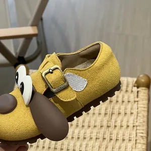 Close-up detail of cartoon dog walking shoe with soft yellow suede and metal buckle.