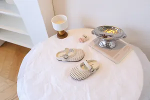 Vue lifestyle de sandales ajourées pour enfants sur une table blanche au style minimaliste