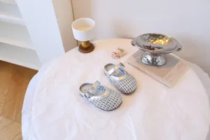 Gros plan de sandales Mary Jane tressées argentées pour filles sur table blanche