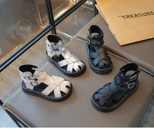 Primer plano de sandalias romanas infantiles en colores plata, negro y crema.