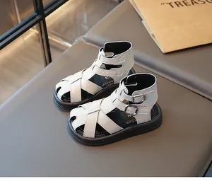 Detalle de sandalias romanas blancas para niños con correas de doble hebilla.