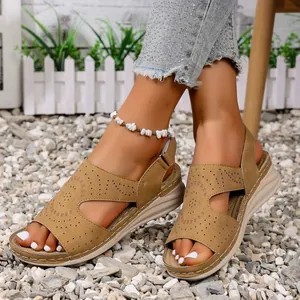 Close-up van bruine platte sandalen met uitsparingen en open teen gedragen op grind